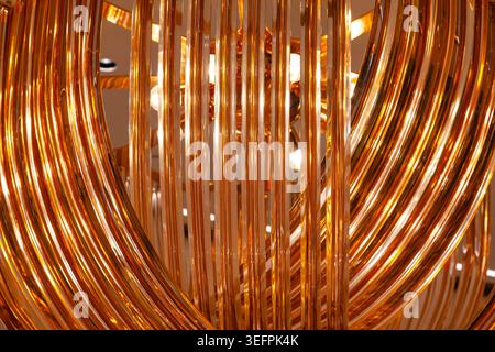 Abstract golden background of glossy metallic wire coils and curved lines with warm glowing light reflection close up Stock Photo