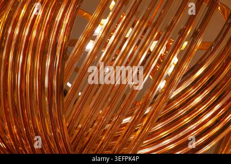 Abstract golden background of glossy metallic wire coils and curved lines with warm glowing light reflection close up Stock Photo