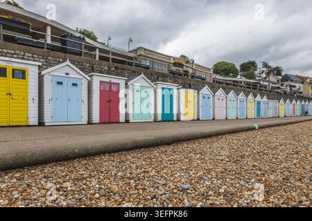 Row of brightly painted beach cabins along a coastal path Stock Photo