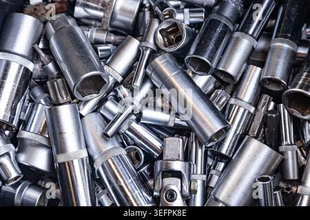 Background pattern of many chrome vanadium steel socket wrenches and assorted mechanic tool parts in a heap top view close up Stock Photo