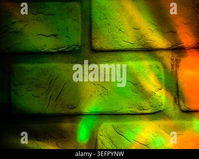 Green and orange glowing reflections illuminating a textured brick wall surface. Abstract decorative background Stock Photo
