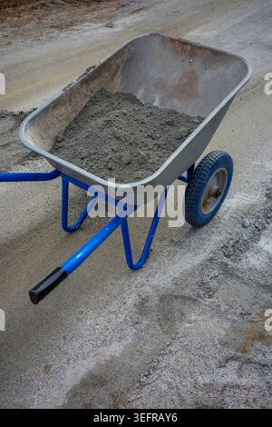 Wheelbarrow with cement on outdoor construction site, close up building detail. Concept: construction work Stock Photo