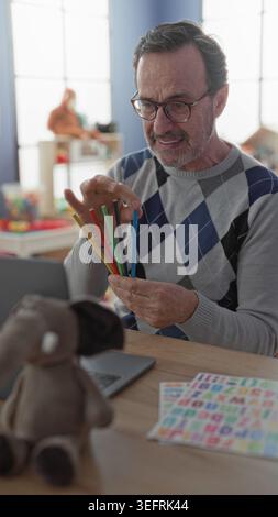Man teacher holding colorful alphabet card and pointing with pencil at ...
