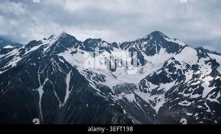 Snow Covered Mountain Range Under Cloudy Sky Stock Photo