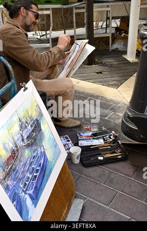 Water colour artist sitting painting a local scene while working in French market in Nice France Stock Photo
