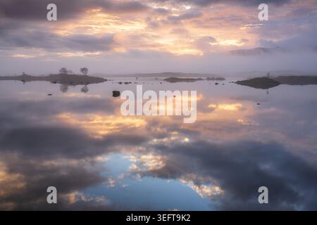 Misty autumn sunrise reflected in Loch Ba on Rannoch Moor in the highlands of Scotland Stock Photo