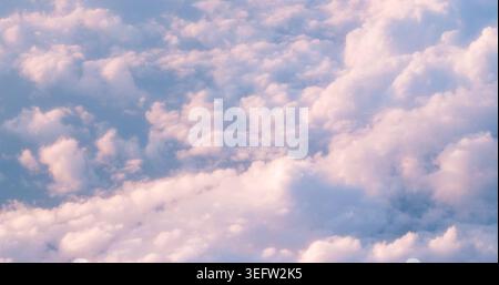 Fluffy pink clouds floating in blue sky Stock Photo