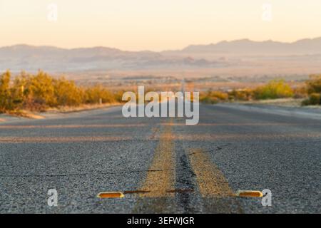 A wide, high-angle view of a lonely road descending into the vast Mojave Desert basin toward Twentynine Palms, California Stock Photo