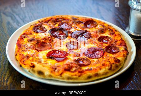 Freshly Baked Pizza Topped With Cheese and Pepperoni Placed on the Restaurant Table. Stock Photo