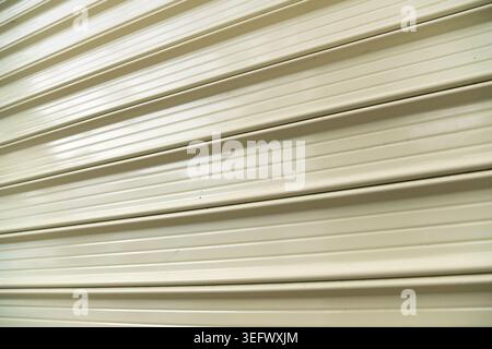 Close-up perspective view of a closed light beige metal roller shutter door. Stock Photo