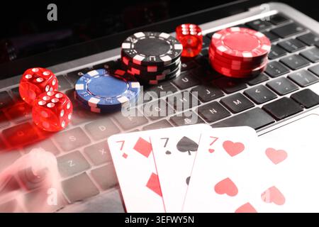 Playing cards, casino chips and dice on laptop in smoke, closeup Stock Photo