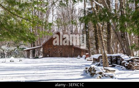 A rustic wooden barn surrounded by fresh snow and forest trees in Althom, Pennsylvania, USA Stock Photo