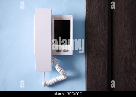 Modern intercom system with handset on light blue wall indoors Stock Photo