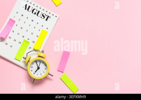 Alarm clock with calendar and sticky notes on pink background. Time management concept Stock Photo