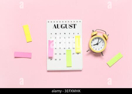 Alarm clock with calendar and sticky notes on pink background. Time management concept Stock Photo