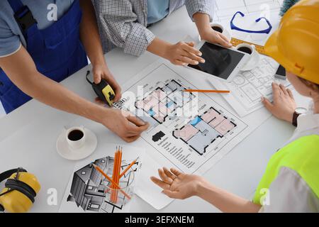 Team of constructors working with house plan at table in office Stock Photo