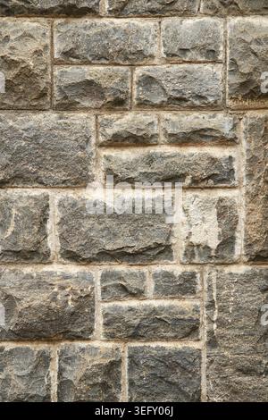 rough chiseled grey stone block masonry wall, old weathered granite surface with uneven brick sizes, full frame background texture Stock Photo