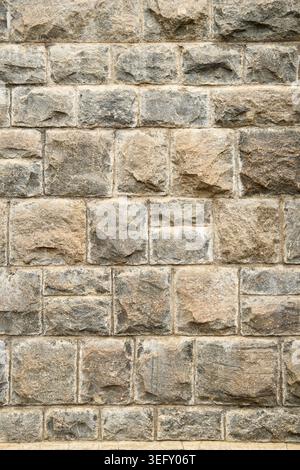 flat rustic grey stone masonry block wall, uniform square and rectangular stones with rough sandy finish, full frame background texture Stock Photo