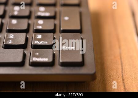 Angled Top View Macro Close-Up Black Computer Keyboard Highlighting Enter Key on Numeric Keypad on Blurred Tech Backgrounds Stock Photo