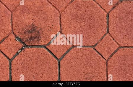 Top-down full-frame view of red interlocking octagon and square concrete paving tiles forming a textured outdoor surface Stock Photo