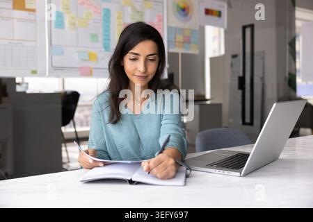 Young professional woman writes in notebook while holds documents Stock Photo