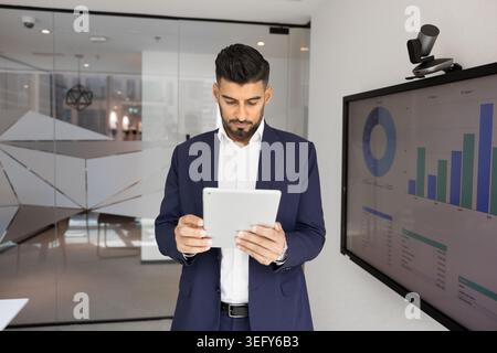 Indian businessman analyzing data on tablet in office Stock Photo