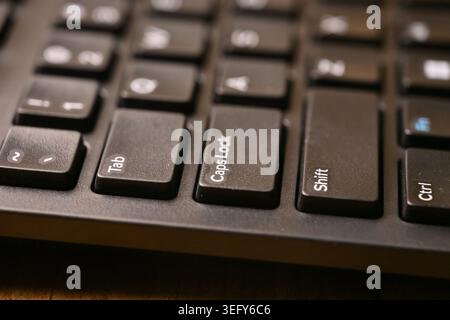 Side Angled Top View Macro Close-Up Black Computer Keyboard Highlighting Caps Lock Key on Blurred Tech Backgrounds Stock Photo