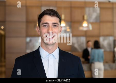 Headshot portrait of smiling male receptionist standing at hotel lobby Stock Photo