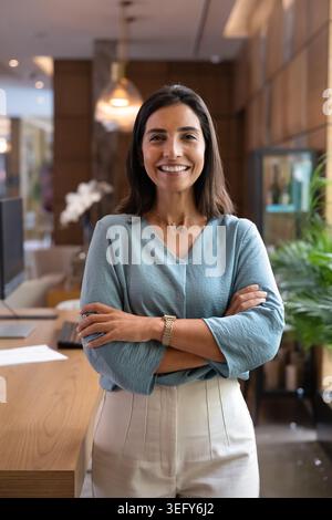 Portrait of receptionist standing with arms crossed in hotel reception Stock Photo