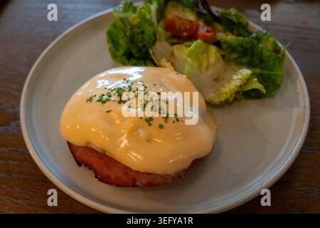 Eggs Benedict served on plate. It is a common American breakfast or brunch dish, consisting of two halves toast topped with bacon, poached egg, and ho Stock Photo