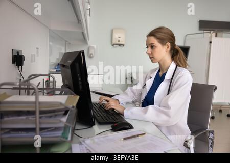 Focused female doctor working on computer in clinic office Stock Photo