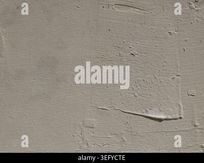 Close-up of a light gray concrete surface showing subtle trowel strokes, fine aggregate, pores, and a thin scratch, creating a rough, industrial backg Stock Photo
