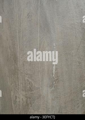 Close-up of a gray concrete wall showing rough, grainy texture with weathered stains, vertical streaks and speckled mineral patterns, ideal as an indu Stock Photo