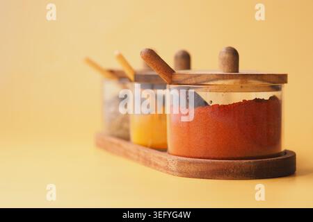 Spice containers arranged on a wooden tray in a kitchen Stock Photo