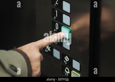 Hand presses elevator button for ground floor Stock Photo