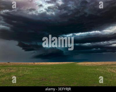 Storm clouds gather over a green landscape.  A thunderstorm is approaching with bad weather on the way. Stock Photo