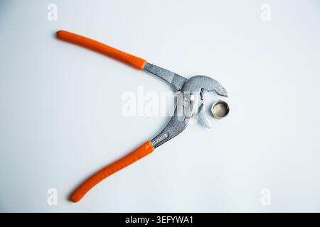 Close-up of the adjustable large wrench is open and between its teeth lies a pipe plug lying on a Stock Photo