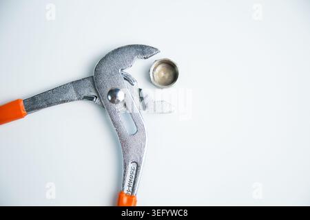 Close-up view of the adjustable large wrench from above is open and between its teeth lies a pipe Stock Photo
