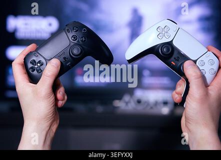 Gorzow Wielkopolski, Poland, 05.16.2026 . White and black PlayStation 5 DualSense controllers in a man's hands. Stock Photo