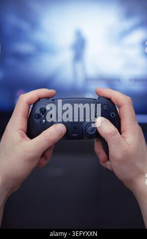 Gorzow Wielkopolski, Poland, 05.16.2026. A man's hands holding a Sony PlayStation 5 DualSense wireless controller in Midnight Black during a game. Stock Photo