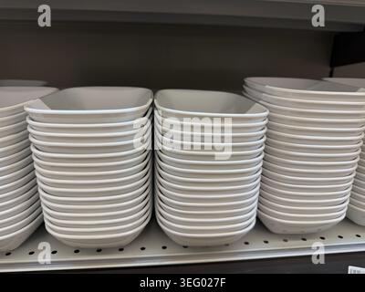 Stacks of white ceramic plates on store shelf, ideal for kitchenware backgrounds. Mobile photo Stock Photo