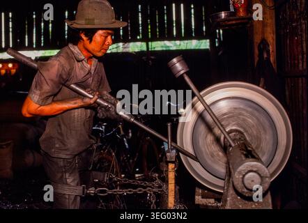 A craftsman working on a metal lathe at a small factory in Phnom Penh, Cambodia, 1987 Stock Photo