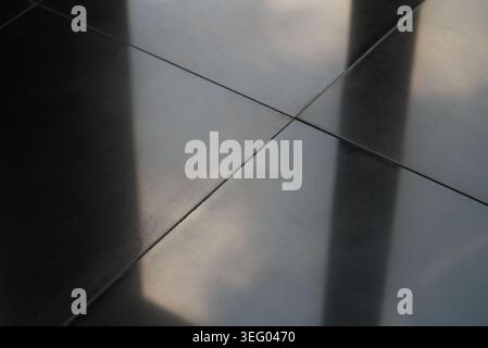 A minimalist, high-angle abstract stock photograph focusing on the geometric pattern of modern interior flooring. The image features dark grey or blac Stock Photo