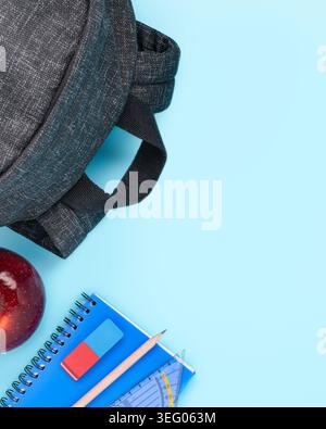 back to school supplies set backpack apple and notebook vertical blue background copy space Stock Photo