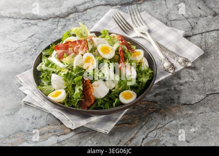 Keto salad with boiled quail eggs, bacon, mozzarella, and mixed lettuce, close-up on a plate on a table. Horizontal Stock Photo