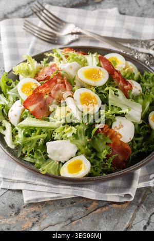Low-carb food salad with quail eggs, bacon, mozzarella and mixed salad close-up in a plate on the table. Vertical Stock Photo