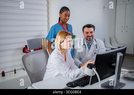 Diverse medical professionals collaborating on patient data using a computer Stock Photo