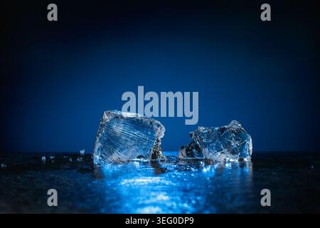 Broken ice with blue backlight on a dark background. Copy space. Stock Photo