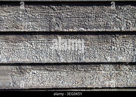 A detailed overhead view of heavily charred and weathered wooden planks. The surface features a rich, scaly texture from fire damage, highlighting aut Stock Photo