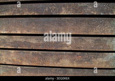 High angle view of weathered dark brown wooden siding planks with horizontal lines and deep shadows. This rustic timber texture highlights authentic a Stock Photo